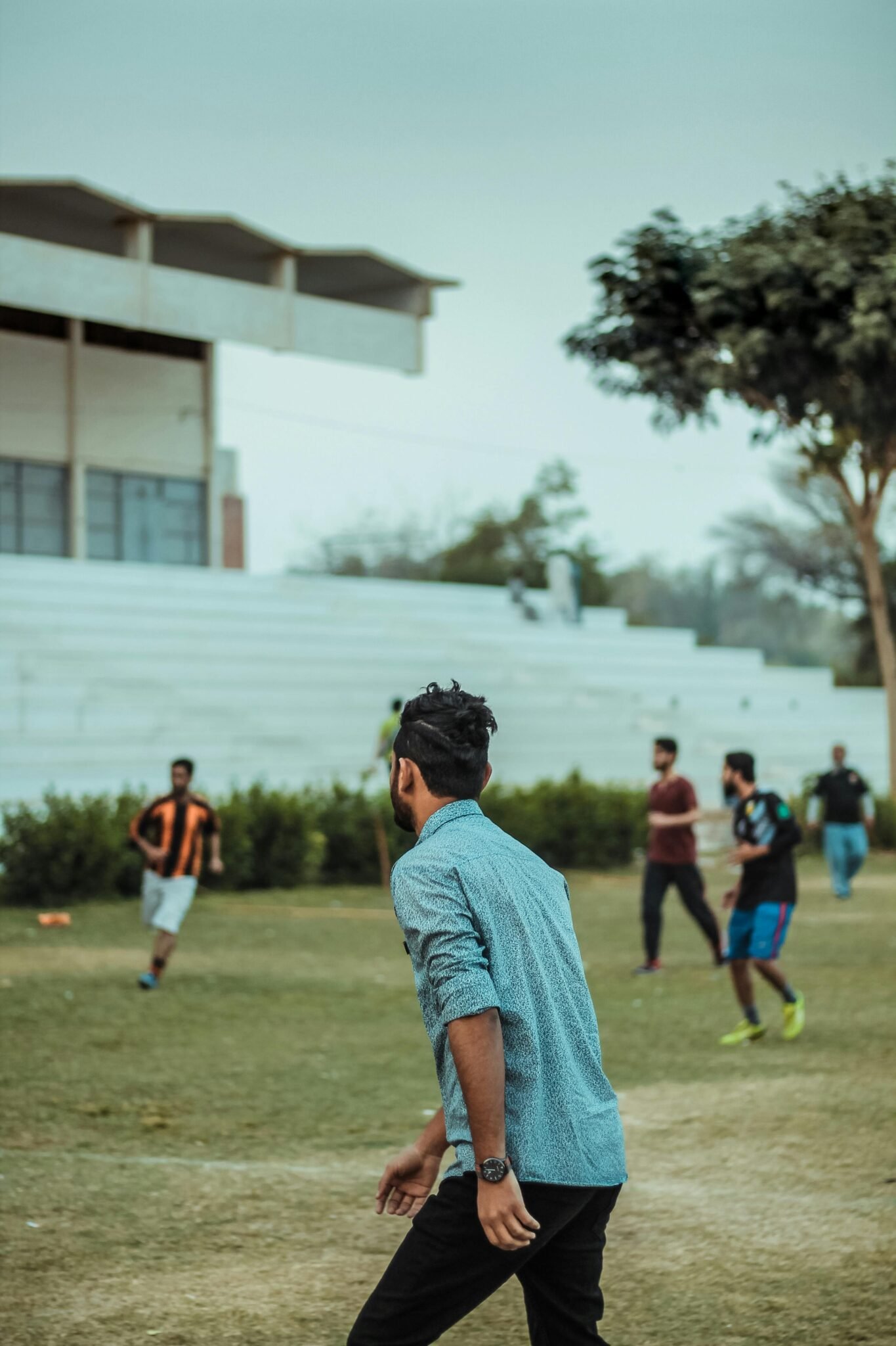 Group of young men playing football outdoors on a grassy field in daylight.